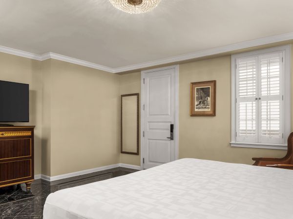 A room with a bed, wooden TV cabinet, mirror, chair, white door, framed picture, and window with shutters.