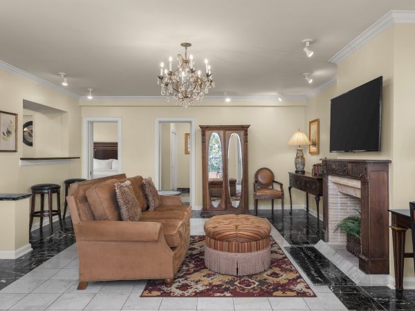 A cozy living room with a brown sofa, chandelier, TV, fireplace, and decor accents, creating a warm and inviting ambiance.
